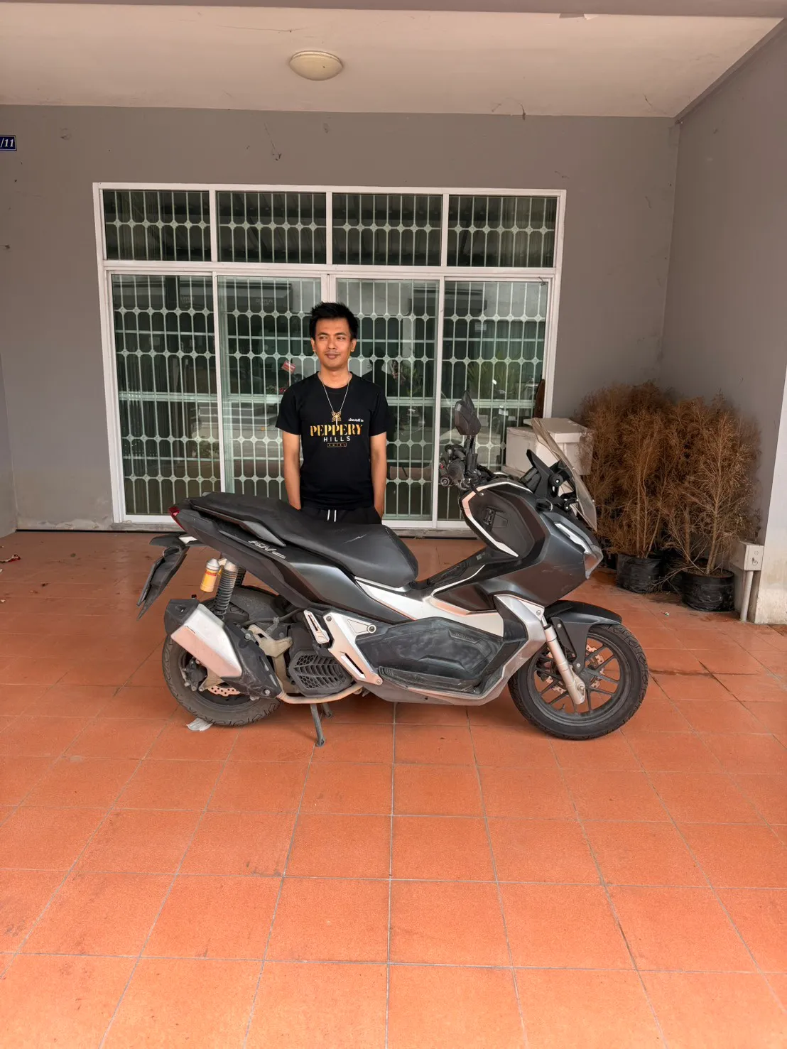 Honda ADV parked in a tiled carport after delivery, its owner standing behind it