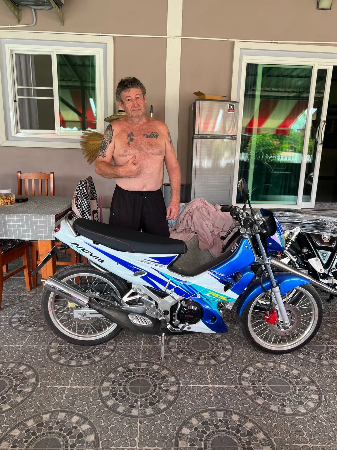 Customer at home with his delivered Honda Nova, a second bike still wrapped beside it